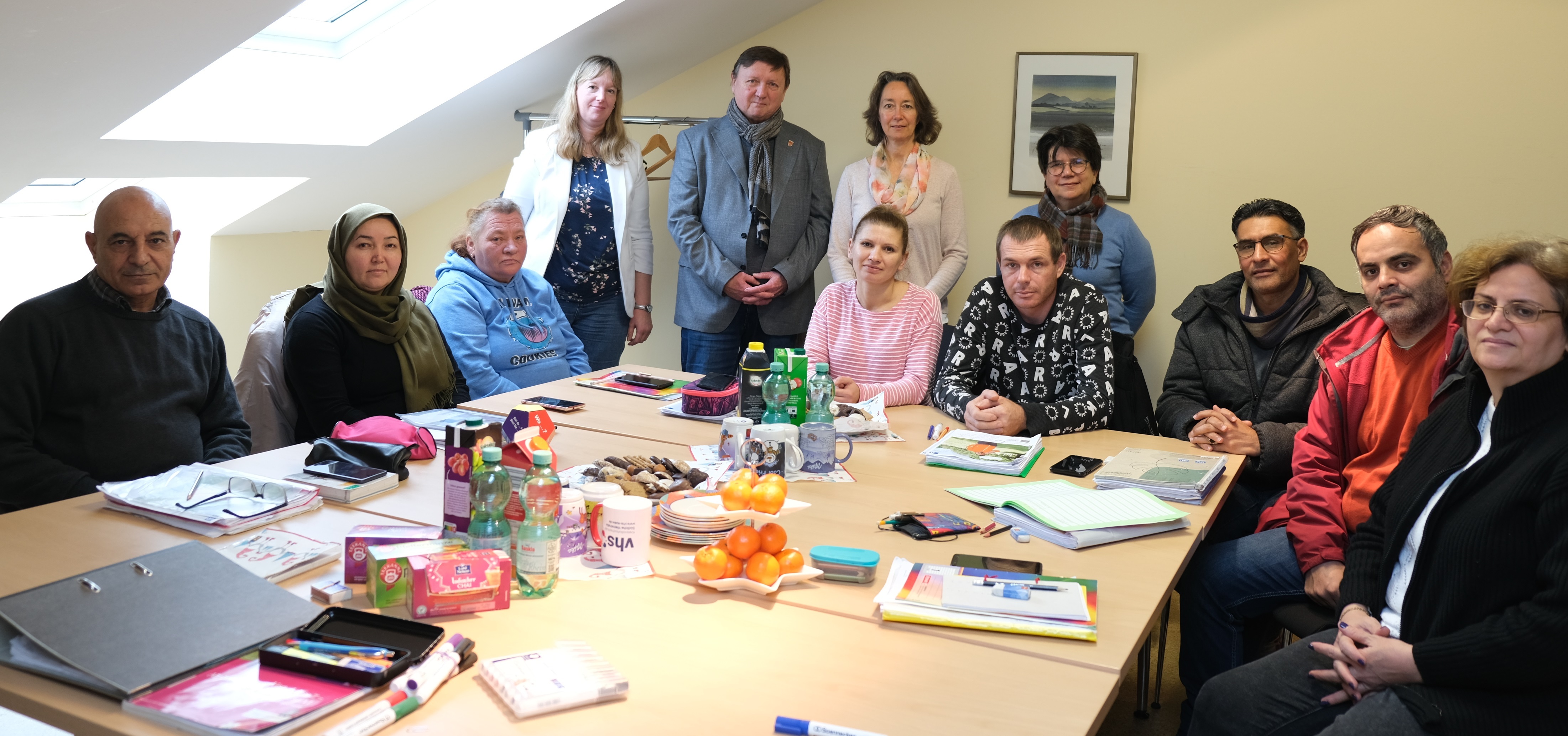 In einem Kursraum sitzen oder stehen mehrere Personen. 