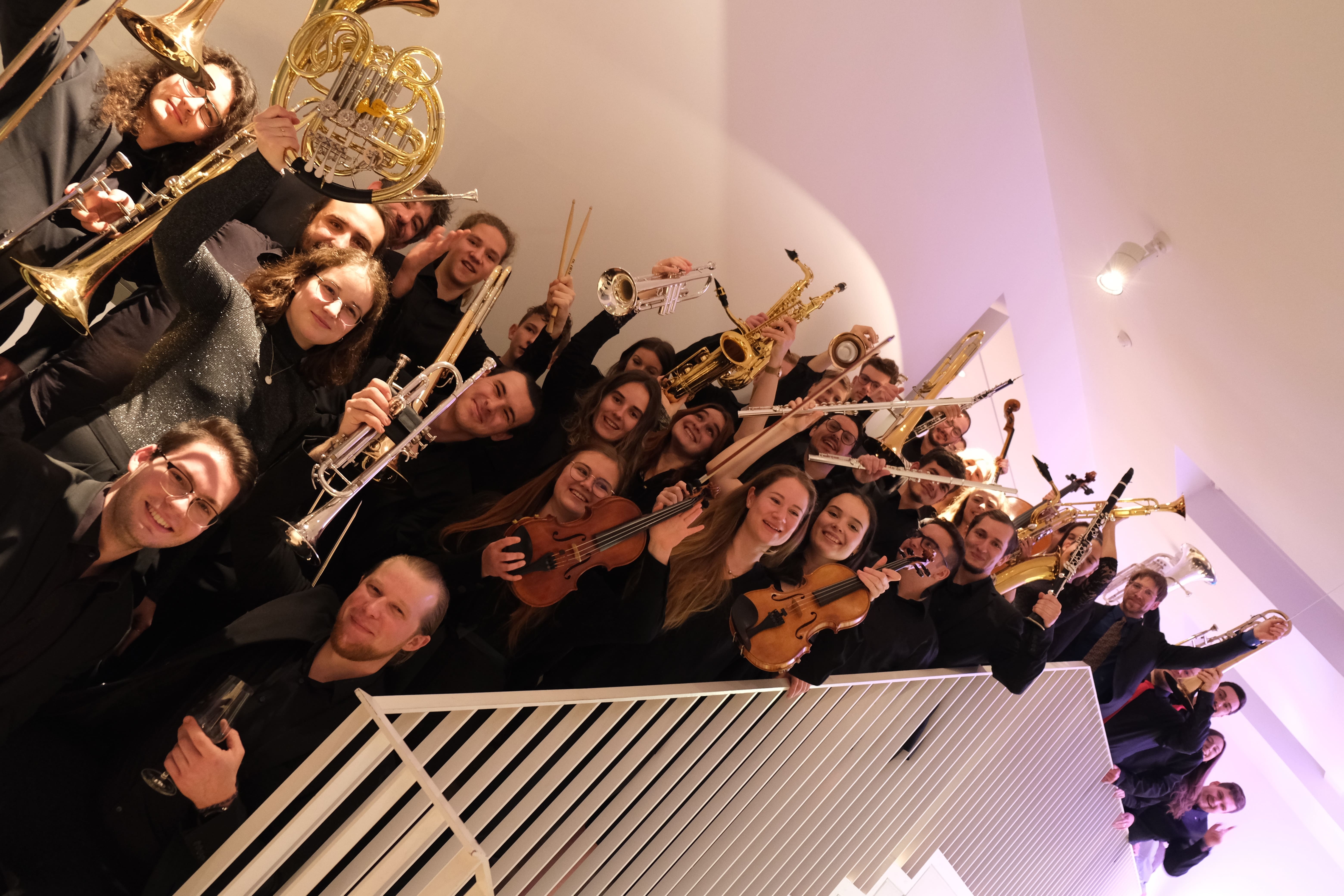 Eine Gruppe junger Leute mit Instrumenten auf einer Treppe. 