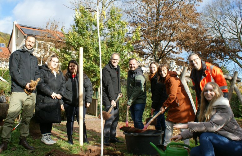 Der Maulbeerbaum steht! Zum Abschluss der Aktion auf dem Spielplatz neben der Grundschule St. Martin. Foto: KV SÜW Eine Gruppe Menschen mit einem frisch gepflanzten Baum.