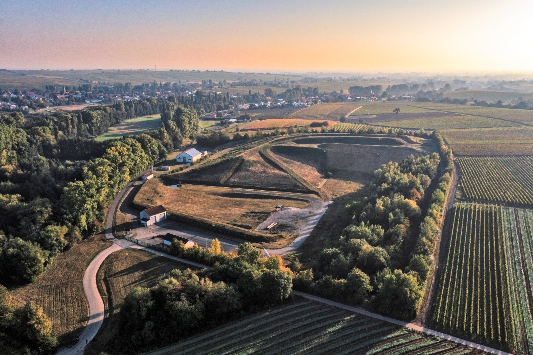 Eine größere Deponieanlage, umgeben von Weinbergen. 