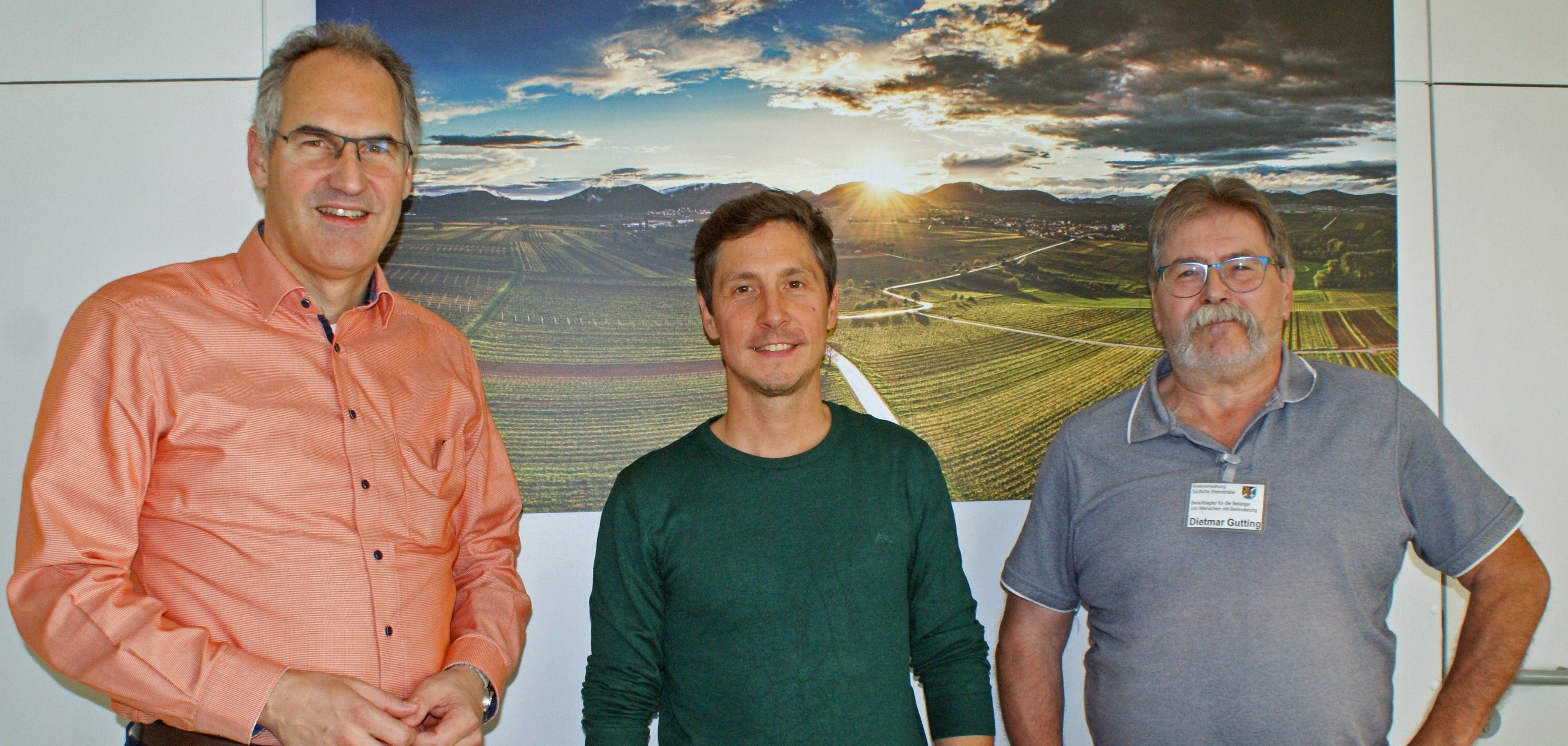 Landrat Dietmar Seefeldt, Sportinklusionslotse Benjamin Joest und SÜW- Inklusionsbeauftragter Dietmar Gutting stehen gemeinsam vor einem Landschaftsfoto. 