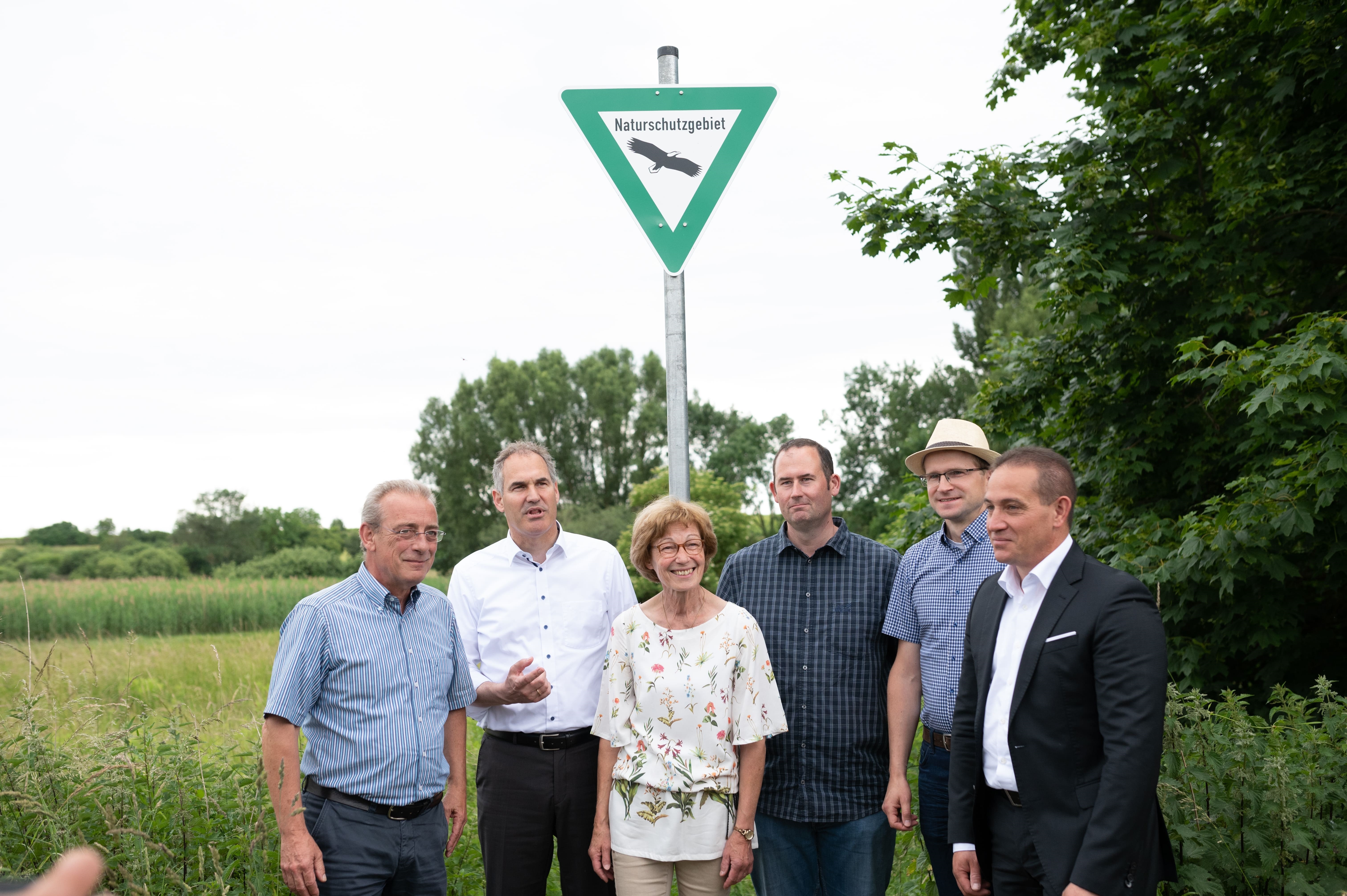 Fünf Personen stehen unter dem Hinweisschild "Naturschutzgebiet" im Freien.