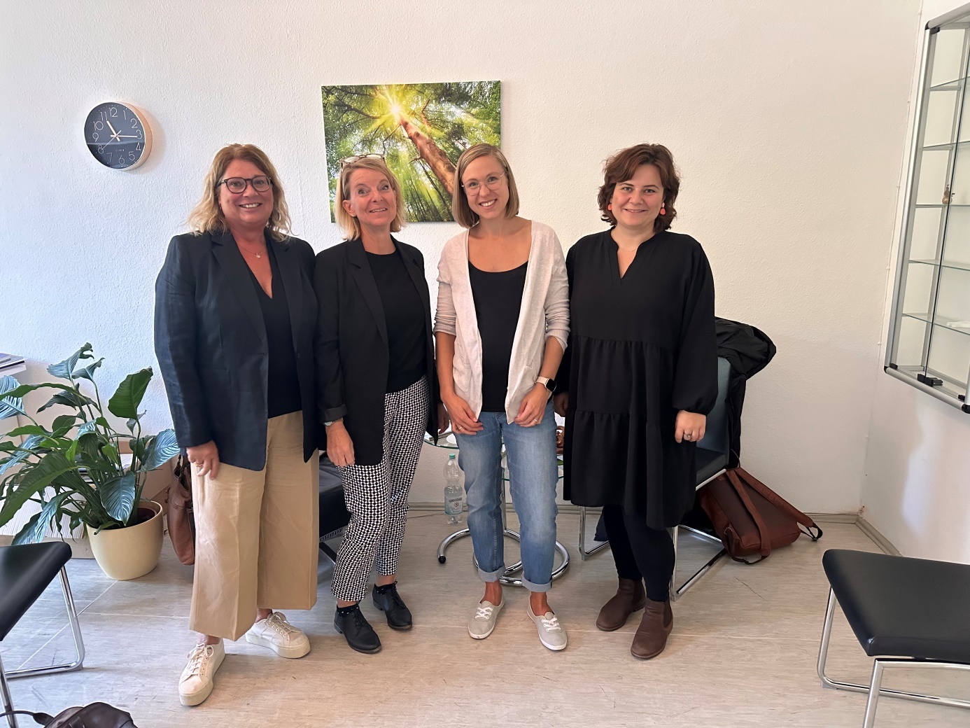 Vier Frauen stehen in einem Beratungsraum. 