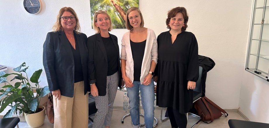 Vier Frauen stehen in einem Beratungsraum. 