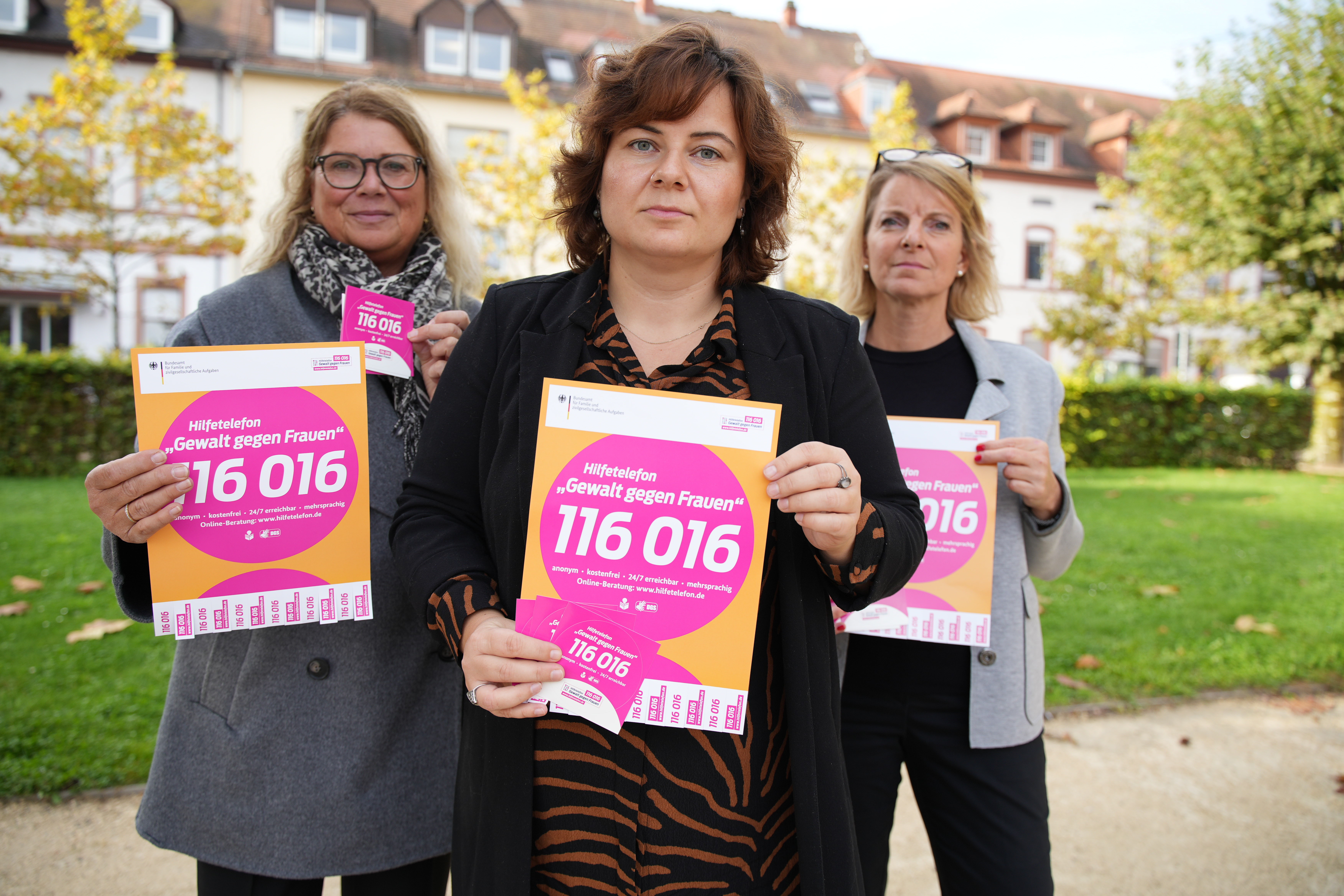 Drei Frauen halten Schilder mit der Telefonnummer 116016 hoch. 