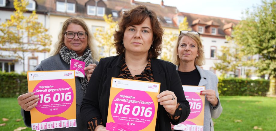 Drei Frauen halten Schilder mit der Telefonnummer 116016 hoch. 