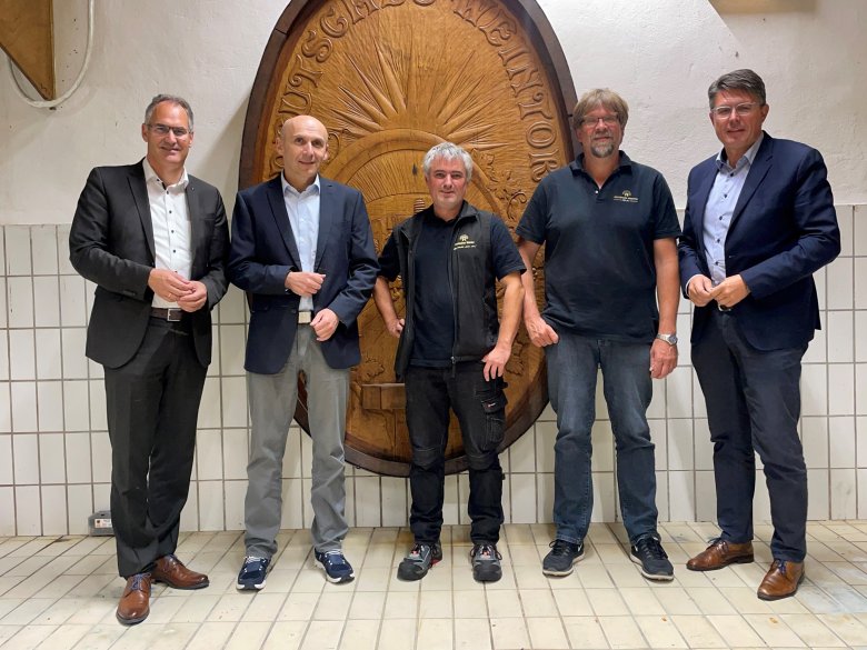 Fünf Männer stehen  vor einem Weinfass.