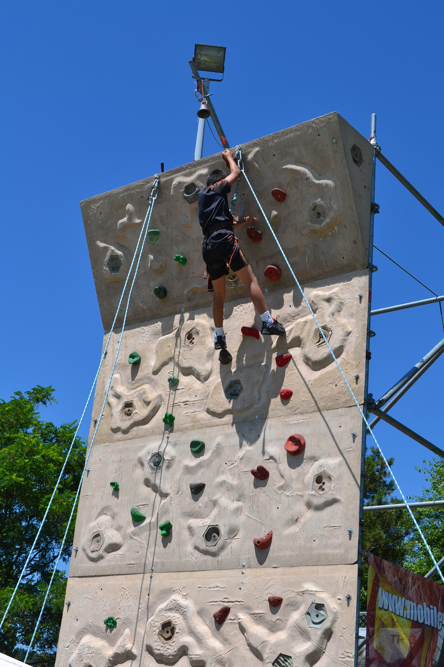 Ein Kind klettert an einer Kletterwand. 