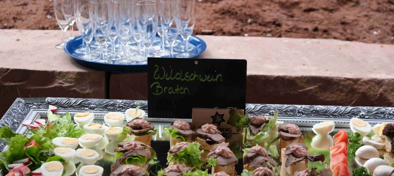 Eine Servierplatte mit Häppchen, darüber ein Schild mit der Aufschrift Wildschweinbraten.