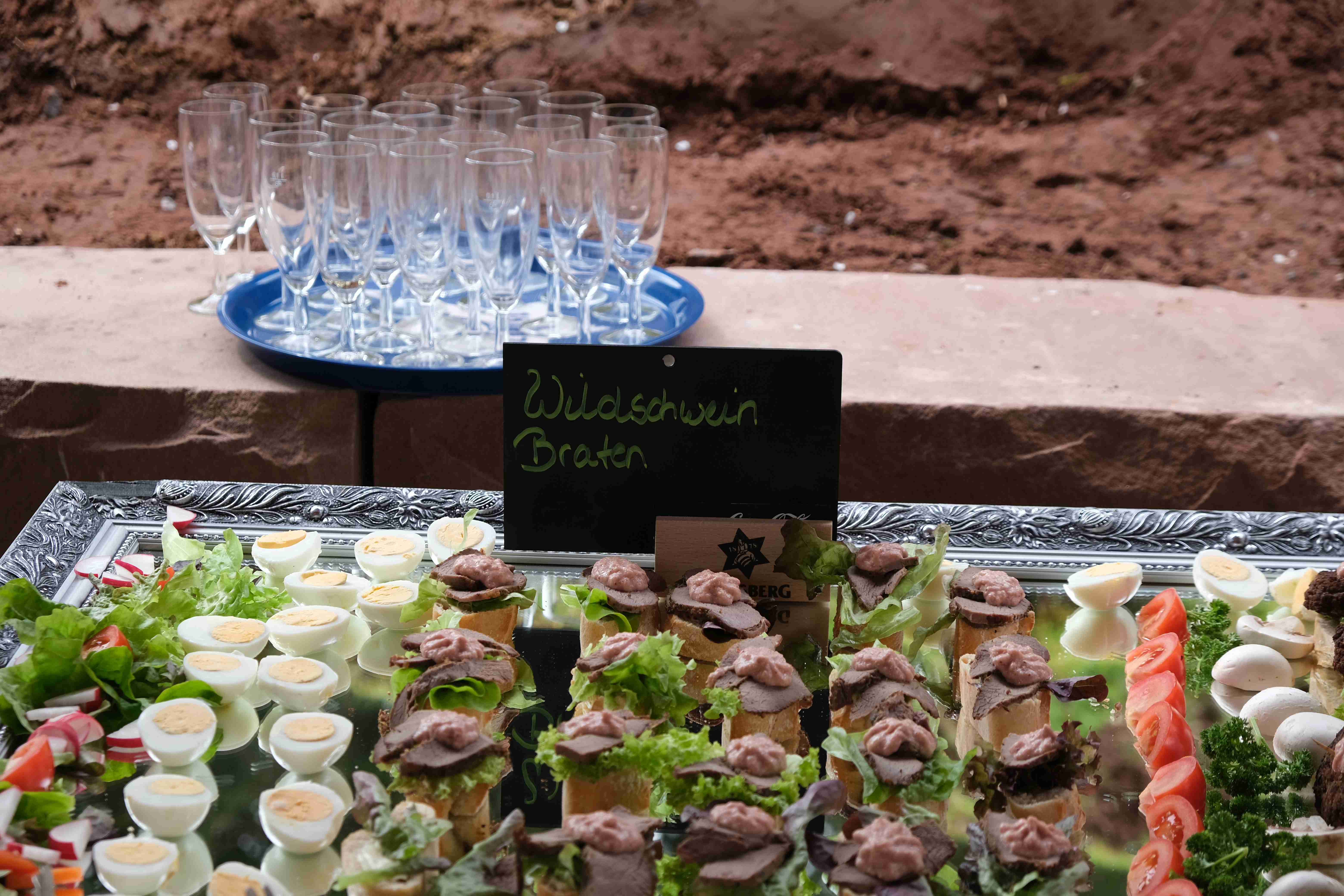 Eine Servierplatte mit Häppchen, darüber ein Schild mit der Aufschrift Wildschweinbraten.