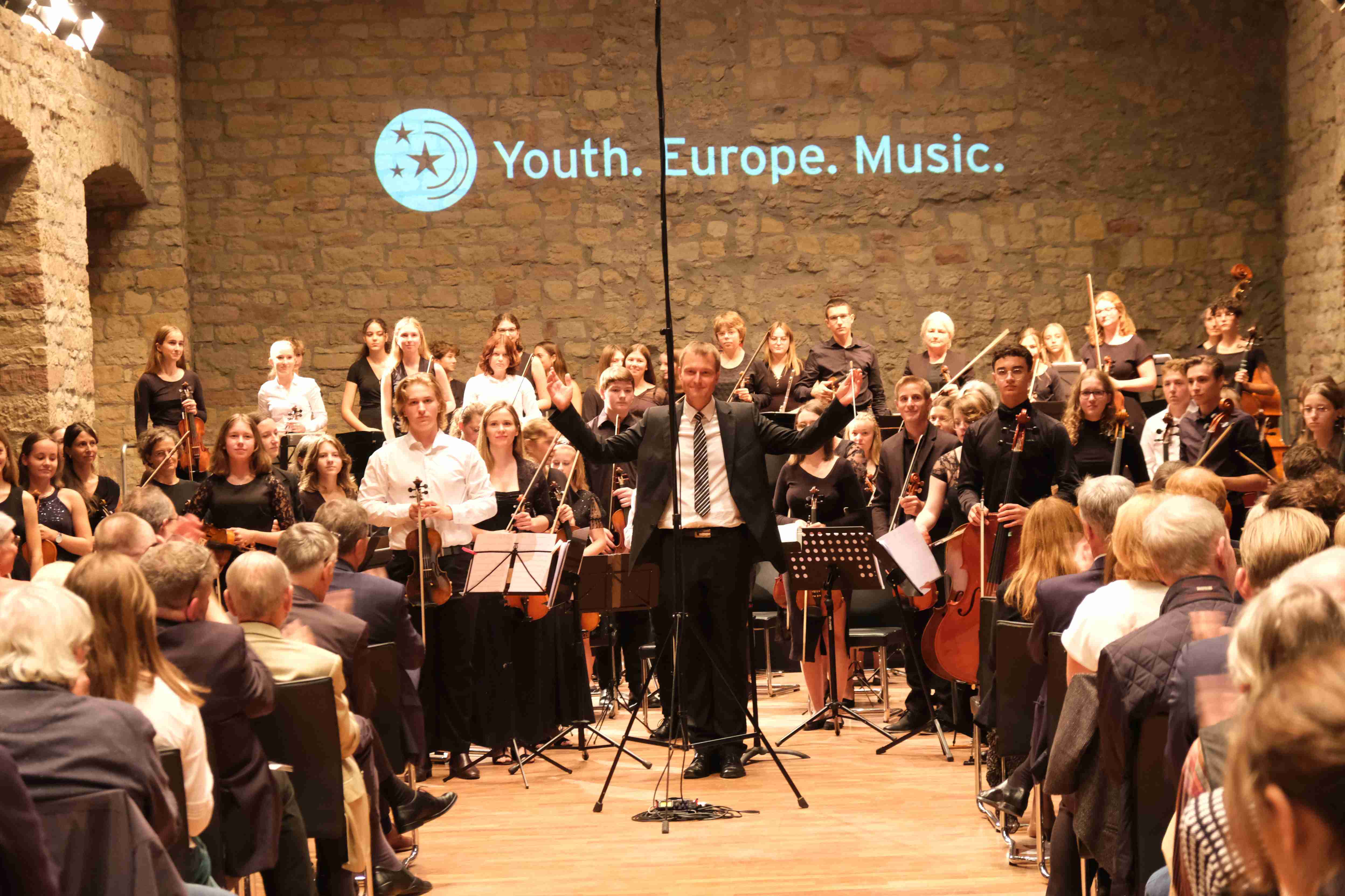 Das trinationale Orchester des Projekts „Youth. Europe. Music.“ unter Marc Bender (in der Mitte) bei einem Auftritt auf dem Hambacher Schloss. Foto: KV SÜW