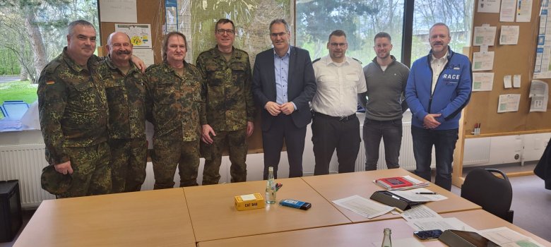 Angehörige des Kreisverbindungskommandos Südliche Weinstraße der Bundeswehr, Landrat Dietmar Seefeldt, SÜW-Brand- und Katastrophenschutzinspekteur Jens Thiele, Tim Hoffmann, Sachbearbeiter im Referat Brand- und Katastrophenschutz der Kreisverwaltung SÜW, und Peter Schürmann, Leiter des im Krisenfall zusammenkommenden SÜW-Verwaltungsstabs. Foto: Bundeswehr Angehörige des Kreisverbindungskommandos Südliche Weinstraße der Bundeswehr, Landrat Dietmar Seefeldt, SÜW-Brand- und Katastrophenschutzinspekteur Jens Thiele, Tim Hoffmann, Sachbearbeiter im Referat Brand- und Katastrophenschutz der Kreisverwaltung SÜW, und Peter Schürmann, Leiter des im Krisenfall zusammenkommenden SÜW-Verwaltungsstabs, stehen in der Kaserne in einer Reihe. Foto: Bundeswehr