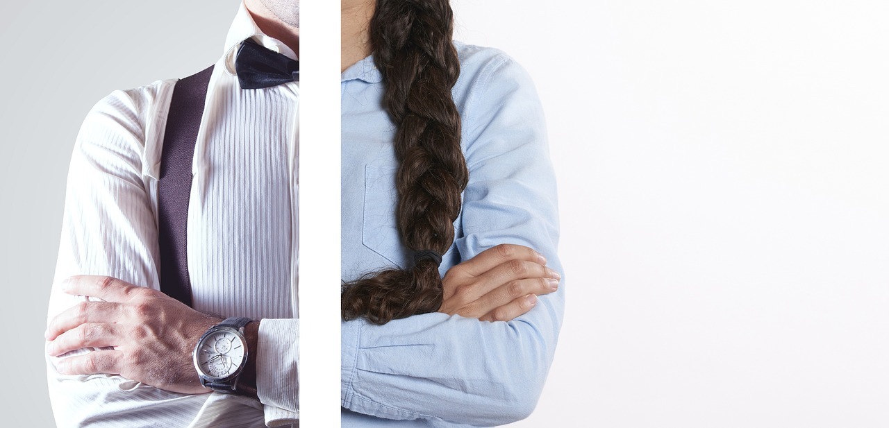 Eine Fotocollage zeigt rechts den Oberkörper einer Frau, links den eines Mannes, jeweils mit vor der Brust verschränkten Armen. Die beiden Bilder sind durch einen weißen Streifen mittig getrennt und zeigen jeweils nur eine Hälfte des Körpers, sodass insgesamt der Eindruck einer aus diesen beiden Hälften zusammengesetzten Person entsteht. Das Bild steht symbolhaft für die Gleichstellung.