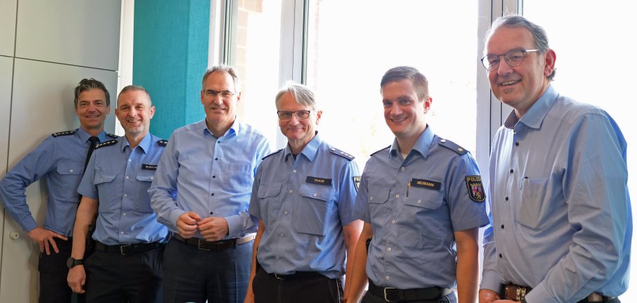 Jürgen Traub beim Besuch von Landrat Dietmar Seefeldt  im Kreishaus in Landau. Mit im Bild zu sehen sind Michael Baron, Leiter Polizeiinspektion Edenkoben, Ralf Burkhard, Leiter Polizeiinspektion Bad Bergzabern, Marc Neumann, Leiter Polizeiinspektion Landau, und Erster Kreisbeigeordneter Georg Kern. Alle stehen gemeinsam vor einer Fensterfront.