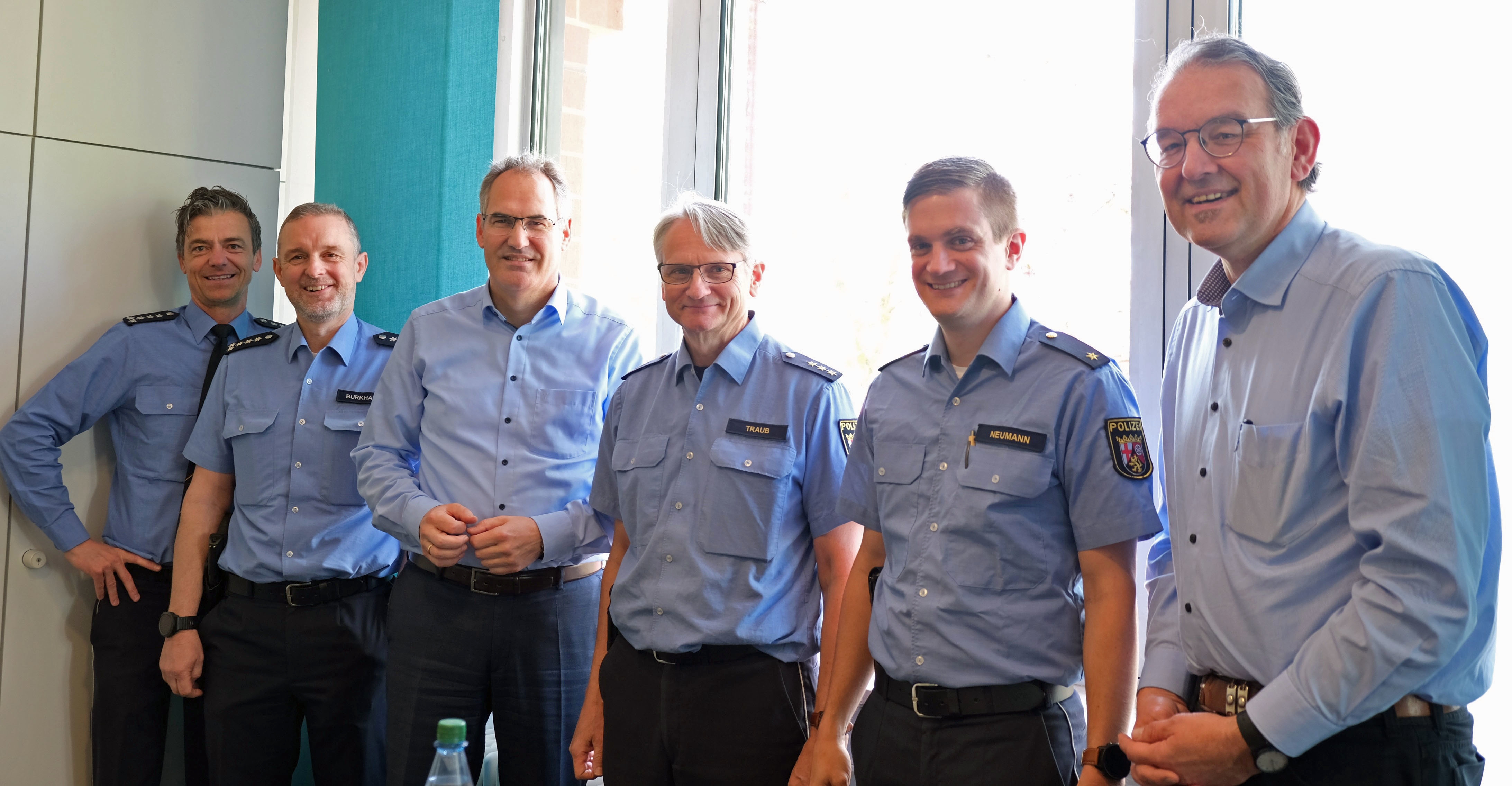 Jürgen Traub beim Besuch von Landrat Dietmar Seefeldt  im Kreishaus in Landau. Mit im Bild zu sehen sind Michael Baron, Leiter Polizeiinspektion Edenkoben, Ralf Burkhard, Leiter Polizeiinspektion Bad Bergzabern, Marc Neumann, Leiter Polizeiinspektion Landau, und Erster Kreisbeigeordneter Georg Kern. Alle stehen gemeinsam vor einer Fensterfront.
