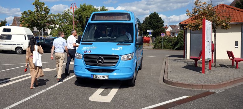 Landrat Dietmar Seefeldt und Bürgermeister Daniel Salm steigen auf dem Parkplatz "Im Letten" in den blauen Kleinbus ein, der im Rahmen der VRNflexline verkehrt. 