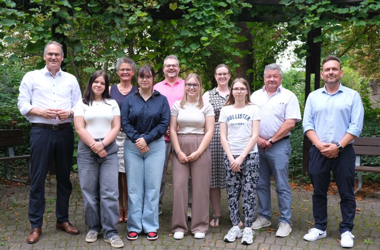 Lysann Schultz, Darlene Wilhelm, Lenie Katharina Kindler und Sophie Herrmann (erste Reihe von links) lassen sich zur Verwaltungsfachangestellten ausbilden. In der zweiten Reihe von links: Landrat Dietmar Seefeldt, stellvertretende interne Gleichstellungsbeauftragte Sabine Huber, Sebastian Renner, Referatsleiter „Personal und Organisationsentwicklung, Zentrale Dienste“, Larissa Conrath, Sachgebietsleiterin Personal, Personalratsvorsitzender Udo Baumgartner und Personalsachbearbeiter Marco Roth. Foto: KV SÜW Eine Gruppe von Menschen im Freien.