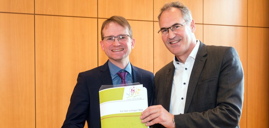 Landrat Dietmar Seefeldt überreichte Daniel Salm, Bürgermeister der Verbandsgemeinde Edenkoben, bei einem Besuch in der Verbandsgemeindeverwaltung die Baugenehmigung für die Grundschule.