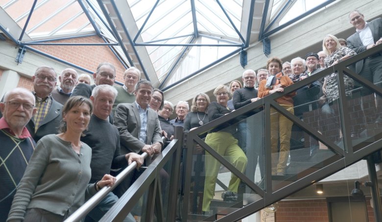 Der neue Seniorenbeirat für den Landkreis Südliche Weinstraße zusammen mit dem Kreisvorstand. Foto: KV SÜW Der neu gewählte Seniorenbeirat des Landkreises Südliche Weinstraße posiert zusammen mit Mitgliedern des Kreisvorstands auf einer Treppe im Foyer der Kreisverwaltung. Die Gruppe steht dicht beisammen und blickt freundlich in die Kamera. Im Hintergrund ist das gläserne Dach des Foyers zu erkennen.