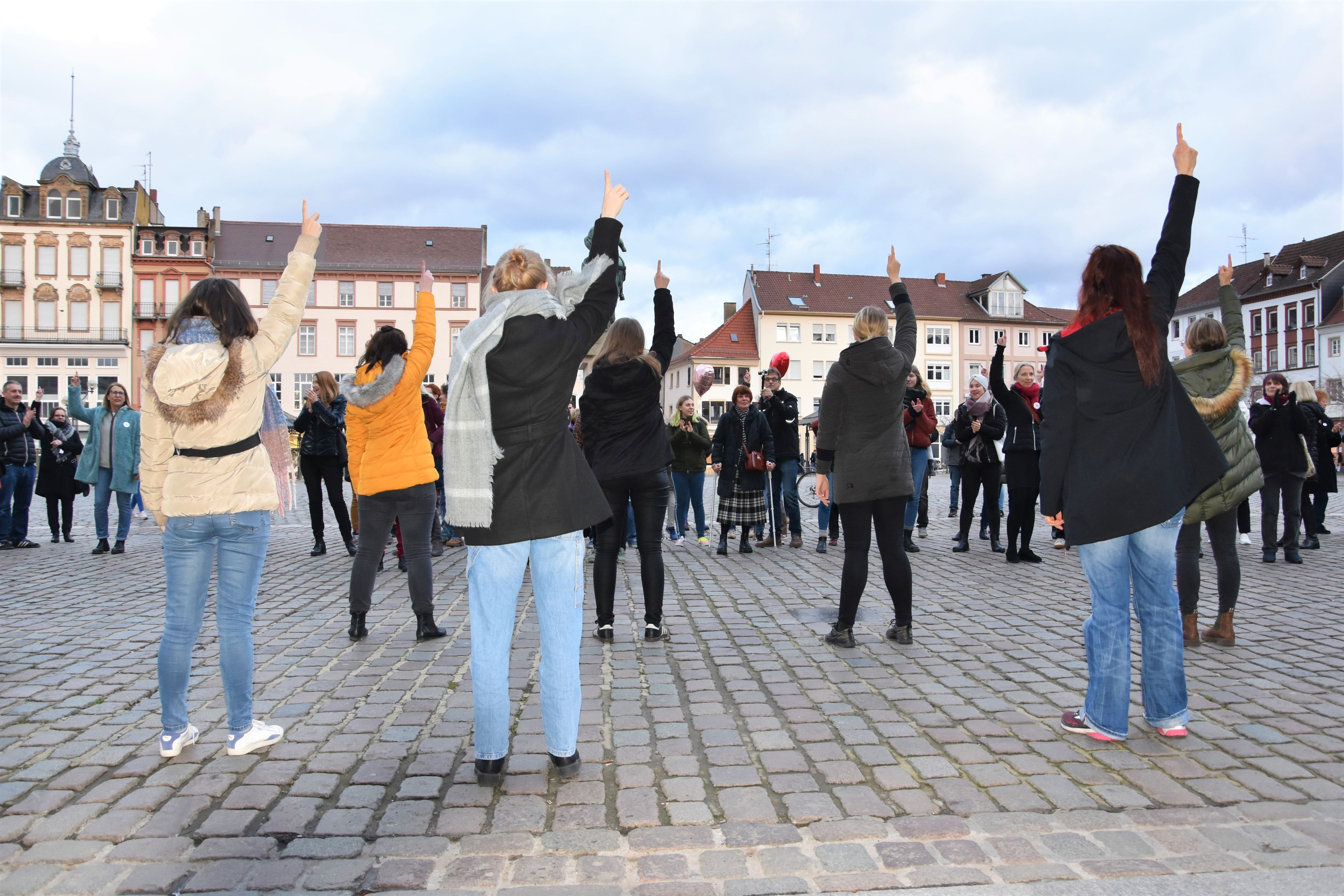 Viele Frauen tanzen auf dem Rathausplatz in Landau und recken die Hände in die Luft.