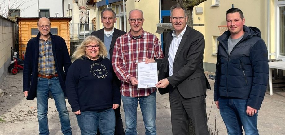 Landrat Dietmar Seefeldt übergab Ortsbürgermeister Jürgen Leibfried (Mitte) den Förderbescheid. Mit im Bild vor der Kita St. Georg: Ortsbeigeordneter Georg Wiedemann, Kita-Leiterin Anke Bruckner, Erster Kreisbeigeordneter Georg Kern und Ratsmitglied Florian Hund.