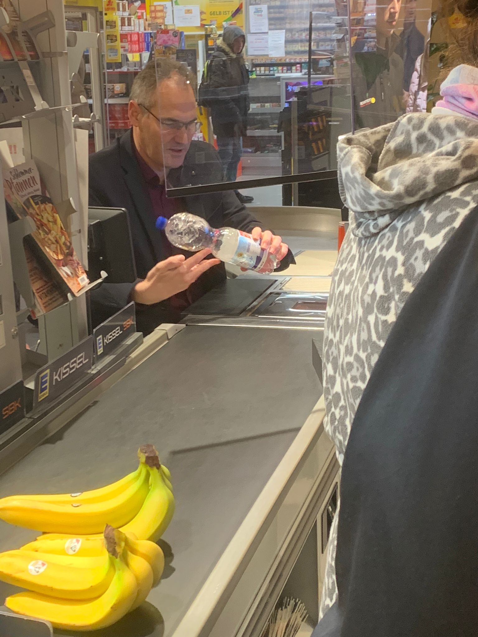 Landrat Dietmar Seefeldt scannt eine Flasche Wasser an einer Supermarkt-Kasse ein.