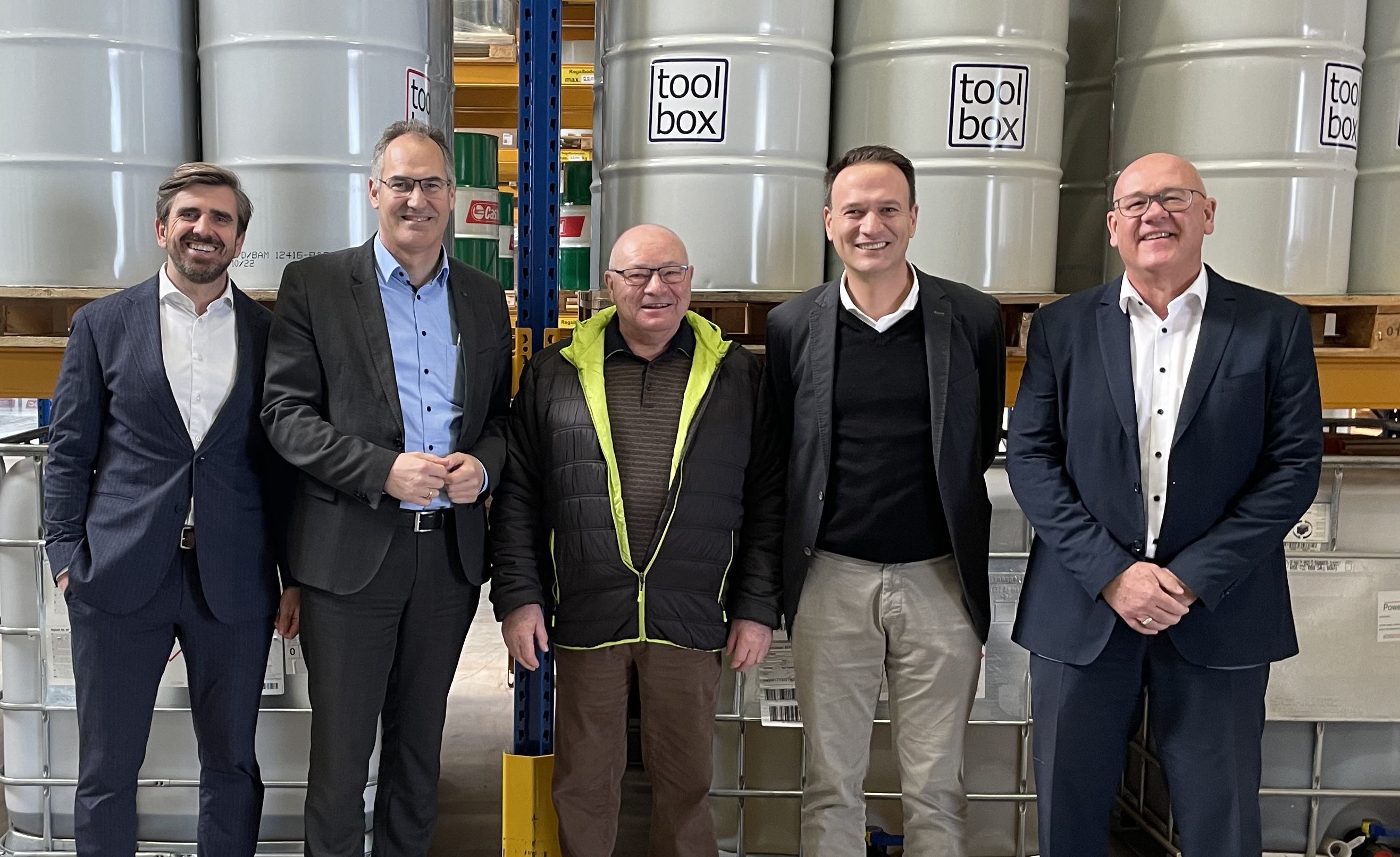 Landrat Dietmar Seefeldt und MBB-Geschäftsführer Uwe König stehen mit dem ehemaligen Geschäftsführer Edgar Schall, dessen Nachfolger Hakan Ög  und dem Geschäftsführer der cobos Fluid Service GmbH, Dennis Bernhardt, in einer Halle des Unternehmens Edgar Schall GmbH in Offenbach. 