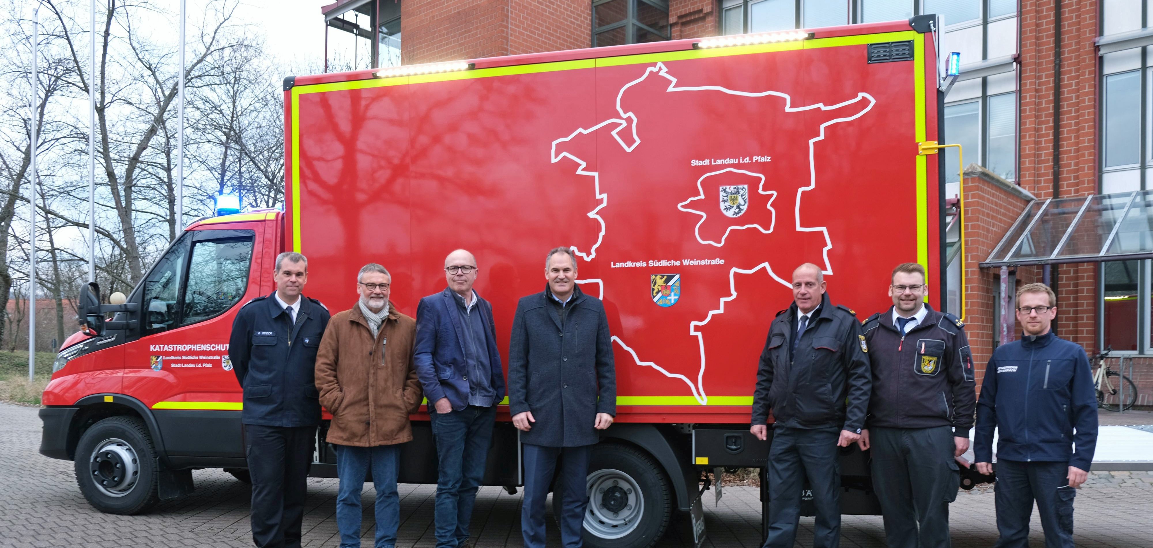 Vertreter des Kreises SÜW und der Stadt Landau sowie der Freiwilligen Feuerwehr Offenbach stehen vor dem neuen Fahrzeug, auf dem das Einsatzgebiet als Grafik zu sehen ist.