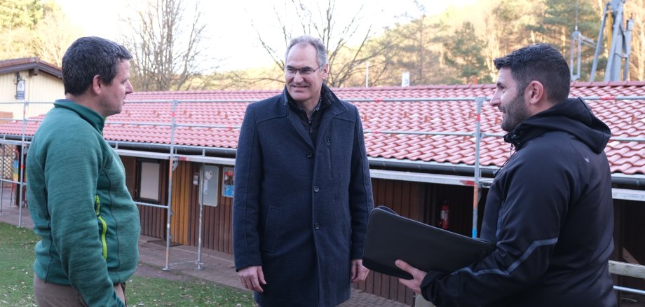 Drei Männer vor einem eingerüsteten Gebäude