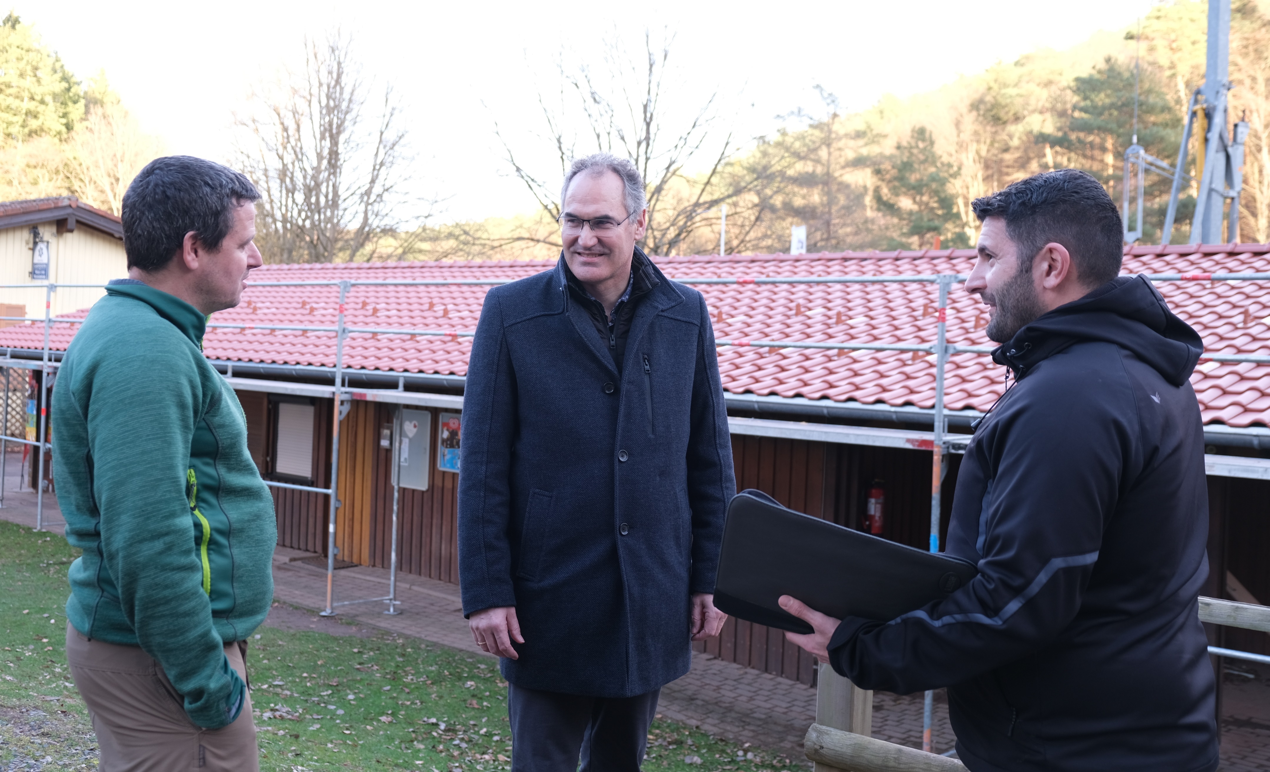Drei Männer vor einem eingerüsteten Gebäude