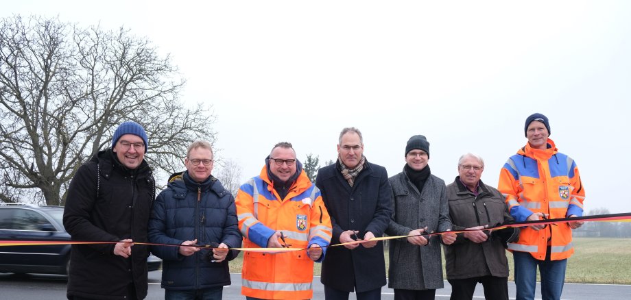 Die Männer stehen an der Straße, im Hintergrund fährt ein Auto. 