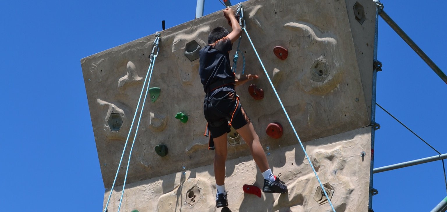 Ein Junge klettert eine Kletterwand im Freien nach oben. Foto: KV SÜW