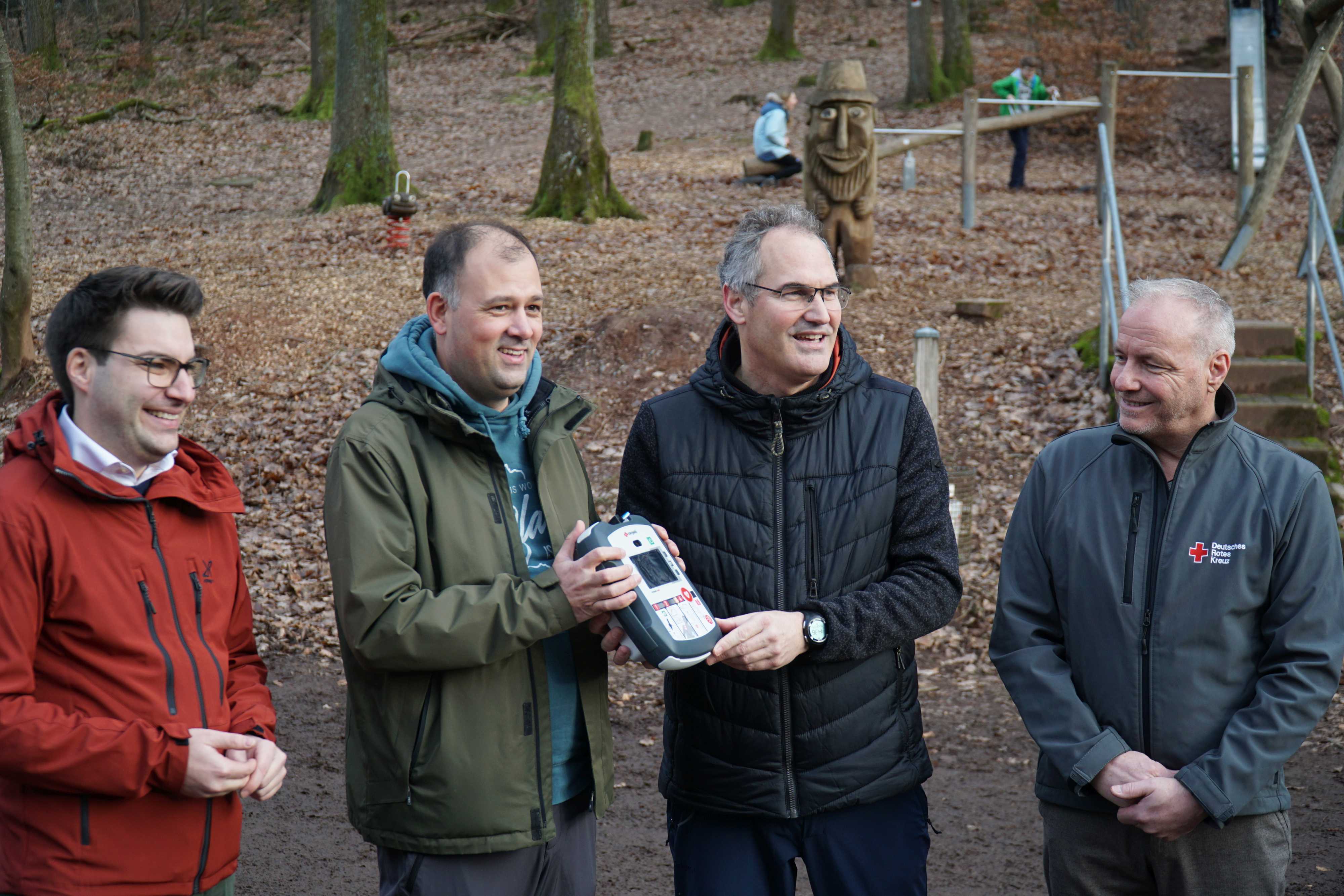 Landrat Dietmar Seefeldt (Zweiter von rechts) überreicht PWV-Hauptvorsitzendem Martin Brandl (Zweiter von links) eines der AED-Geräte im Pfälzerwald. Mit im Bild Benjamin Hirsch (links), Vorstandsmitglied der Sparkasse Südpfalz, und Jürgen See, Geschäftsführer des DRK Kreisverbands Südliche Weinstraße.