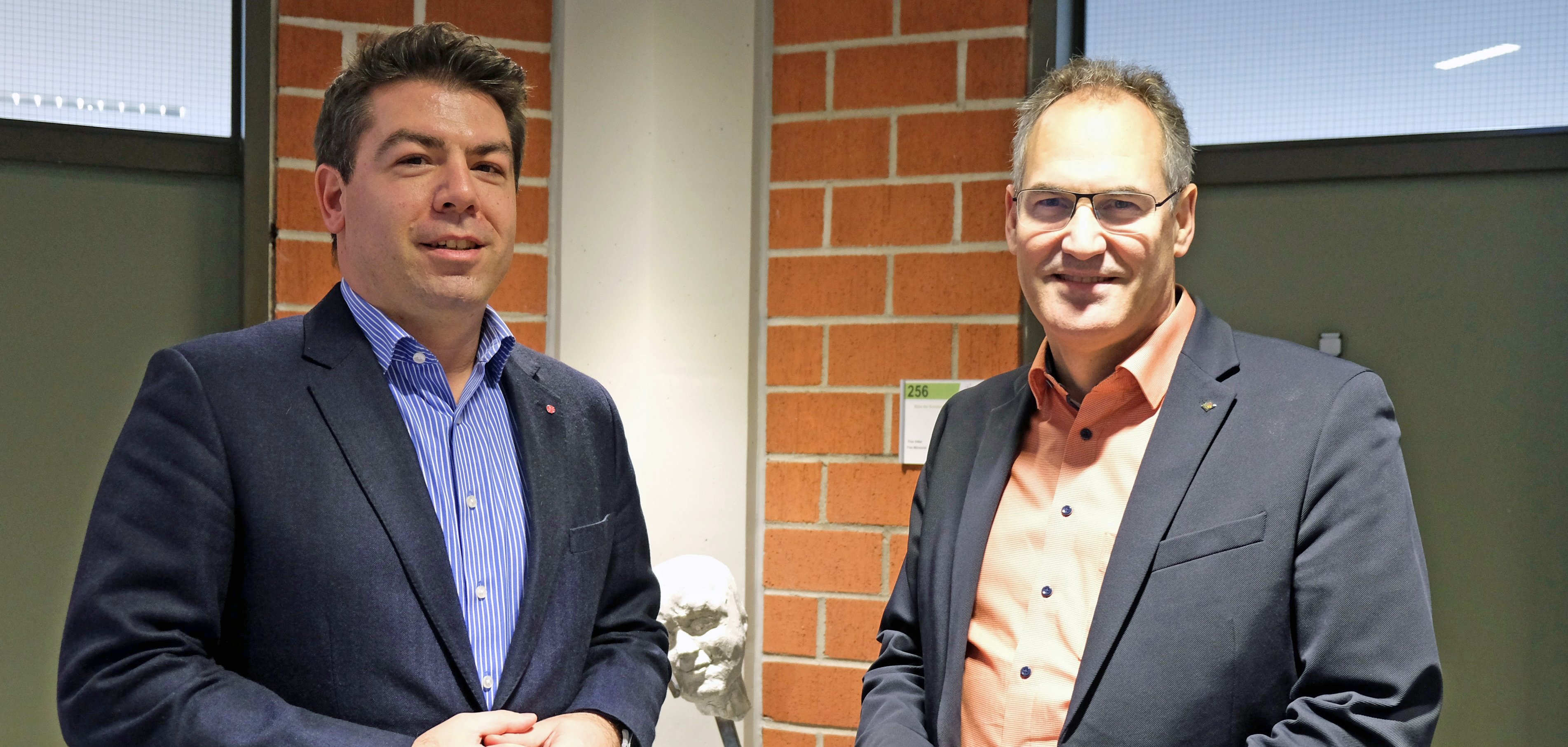 Parlamentarischer Staatssekretär Thomas Hitschler und Landrat Dietmar Seefeldt stehen nebeneinander im Kreishaus. 