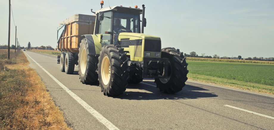 Ein Traktor fährt eine Landstraße entlang. Foto. Pexels