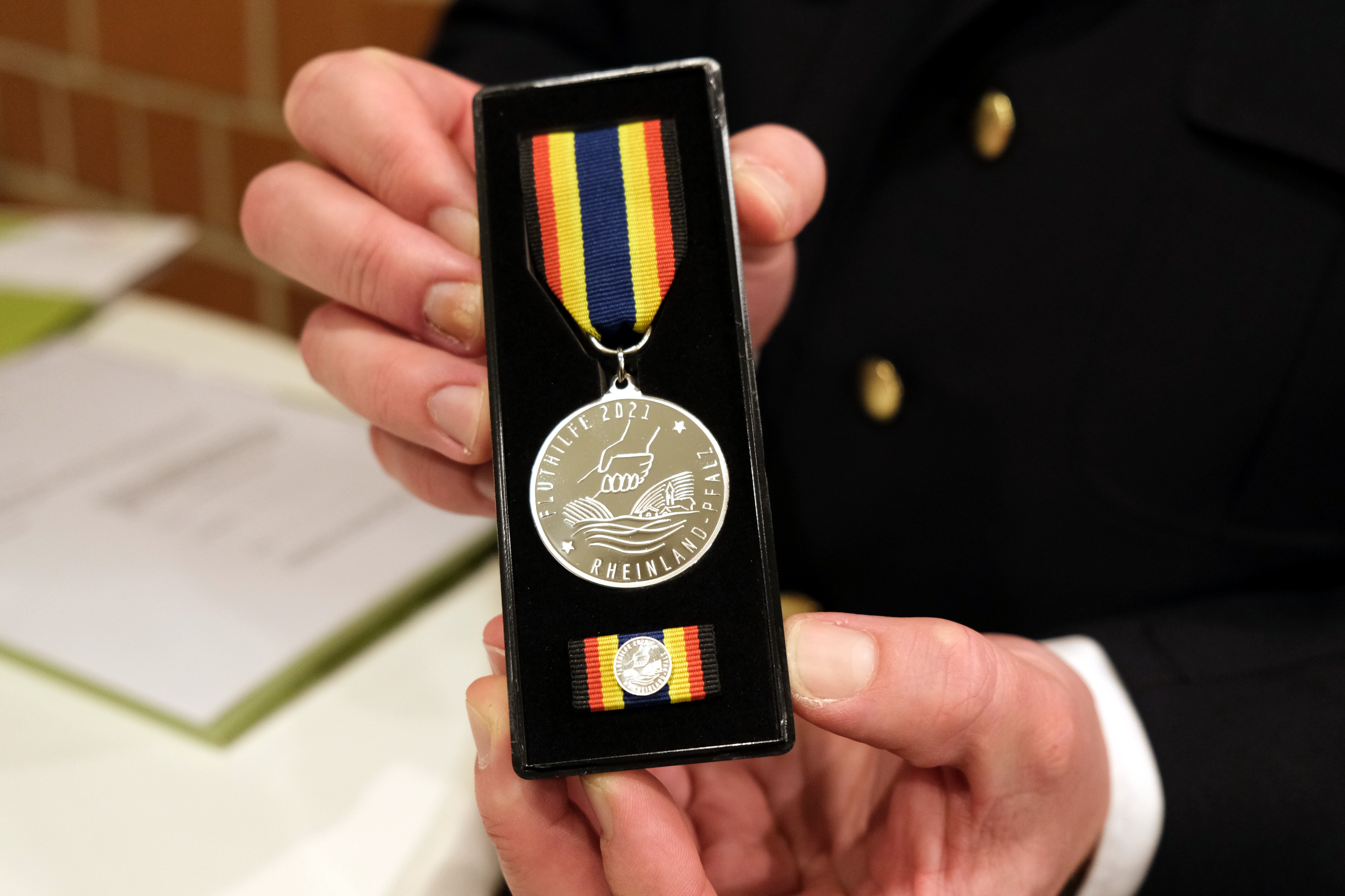 Die Fluthilfemedaille des Landes Rheinland-Pfalz, gehalten in den Händen eines Mannes.