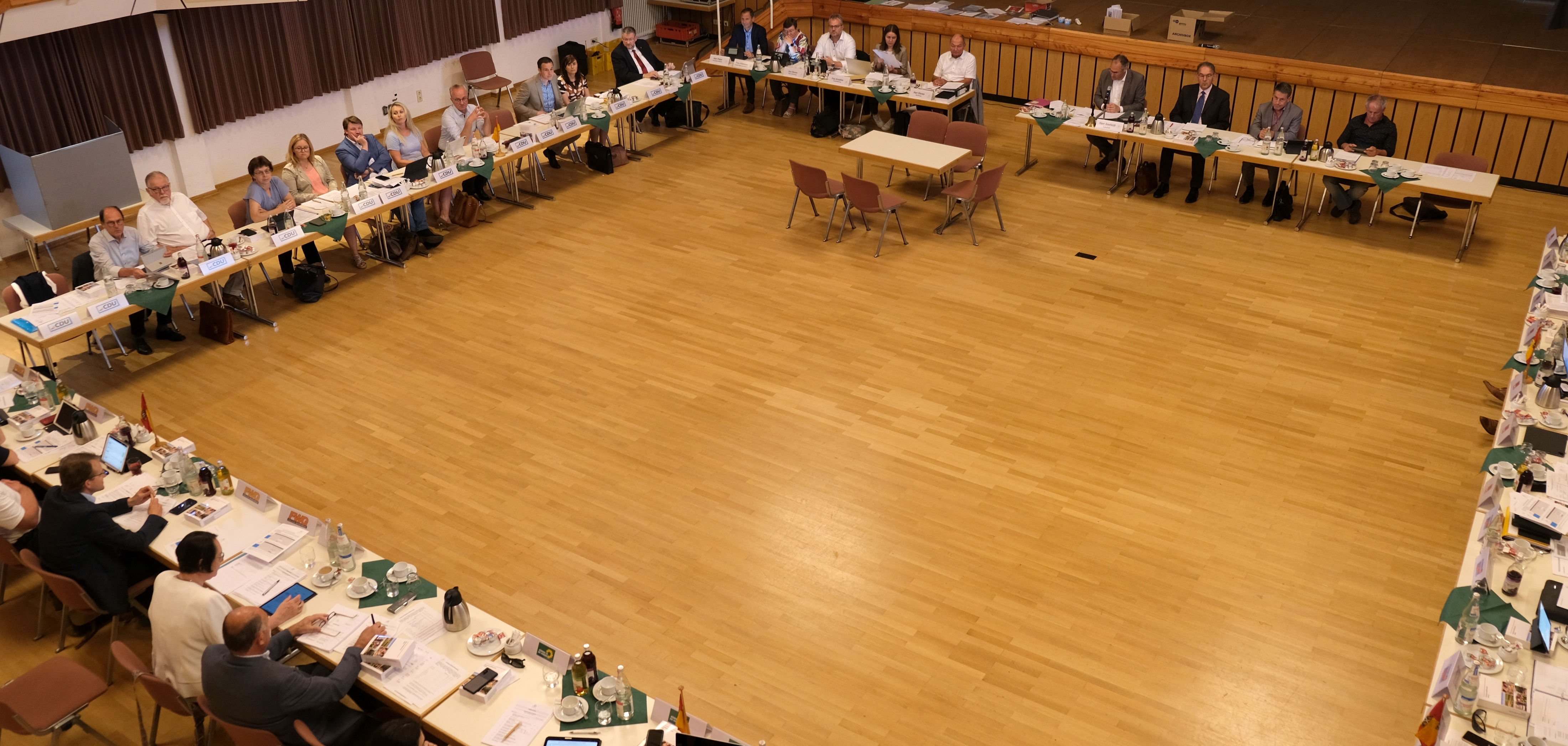 Tische stehen im Quadrat, daran sitzen Menschen. 