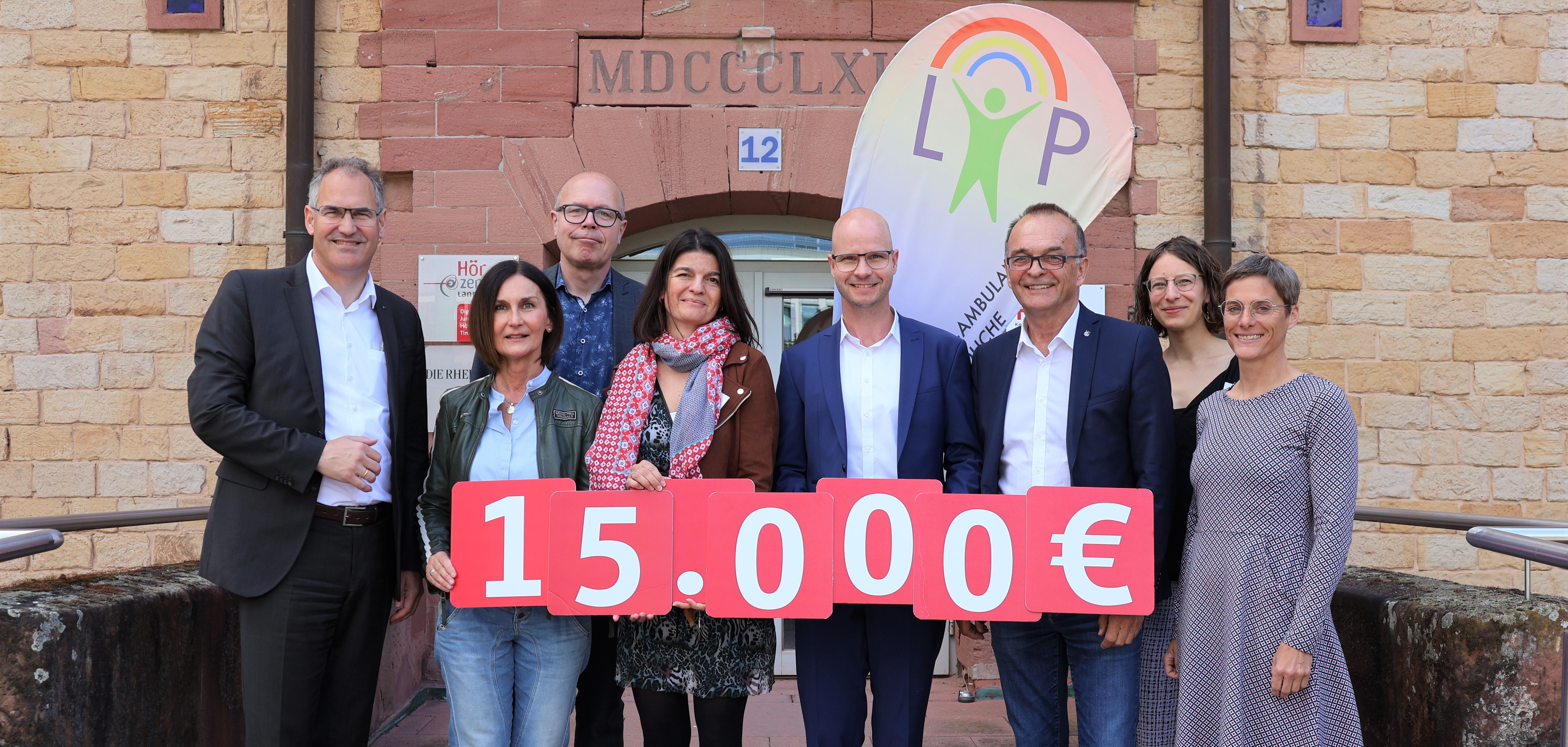Mehrere Personen stehen zusammen und halten ein Schild mit der Aufschrift '15.000 €'. Diese Spende ist für die psychotherapeutische Beratung von Kindern und Jugendlichen bestimmt. Von links nach rechts: Landrat Dietmar Seefeldt, Oberbürgermeister Dominik Geißler, Vorstandsvorsitzender der Sparkasse Südpfalz Svend Larsen und Landrat Fritz Brechtel. Sie überreichen die Spende an die Mitarbeiterinnen der Landauer Psychotherapie-Ambulanz für Kinder und Jugendliche.