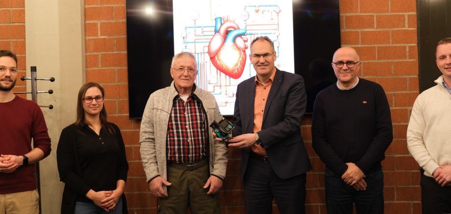 Landrat Dietmar Seefeldt übergibt Florian Hammer im Kreishaus die neue Heizungspumpe. Bei der Übergabe dabei sind außerdem die SÜW-Klimaschutzmanager Philipp Steiner und Fabienne De Pasquale sowie Amar Rezzoug und Jan Augustin von der Haag GmbH in Landau.