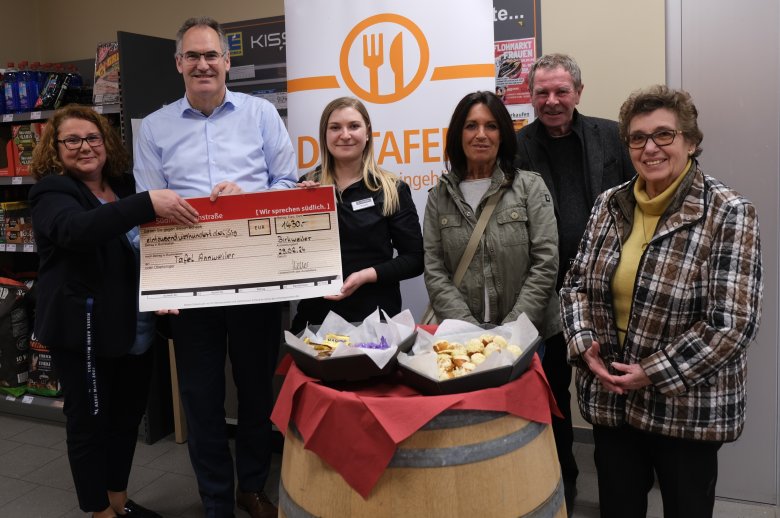 Landrat Dietmar Seefeldt und Mitarbeiterinnen des Edeka Kissel Marktes in Birkweiler übergeben einen Scheck an das Team der Tafel Annweiler.