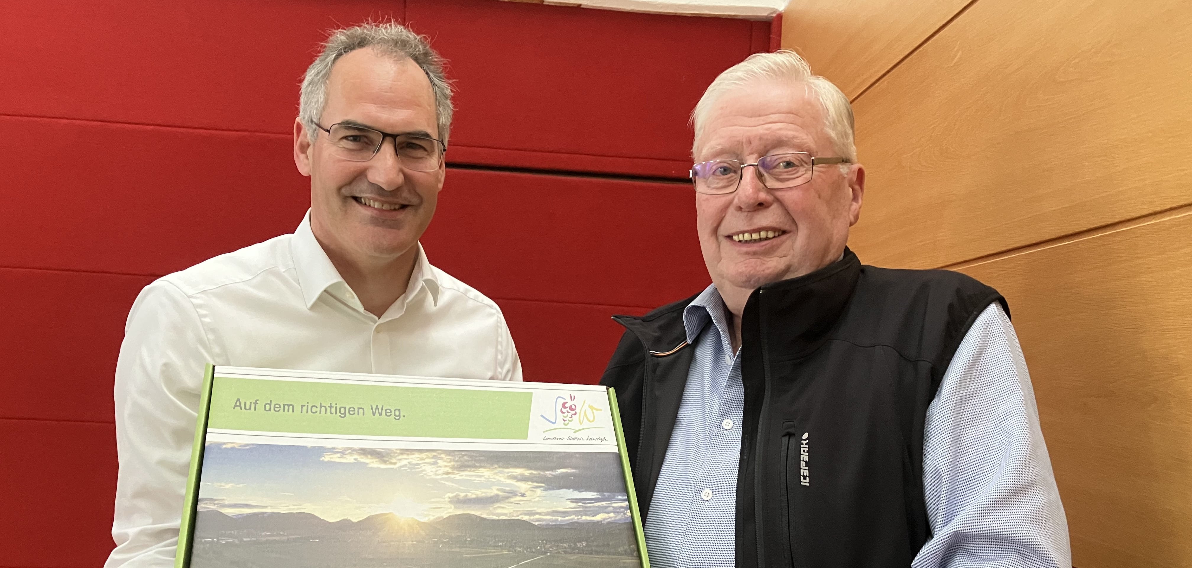 Landrat Dietmar Seefeldt übergibt eine SÜW-Geschenkbox an den scheidenden Vorsitzenden des Kreisseniorenbeirats, Alexander von Rettberg.