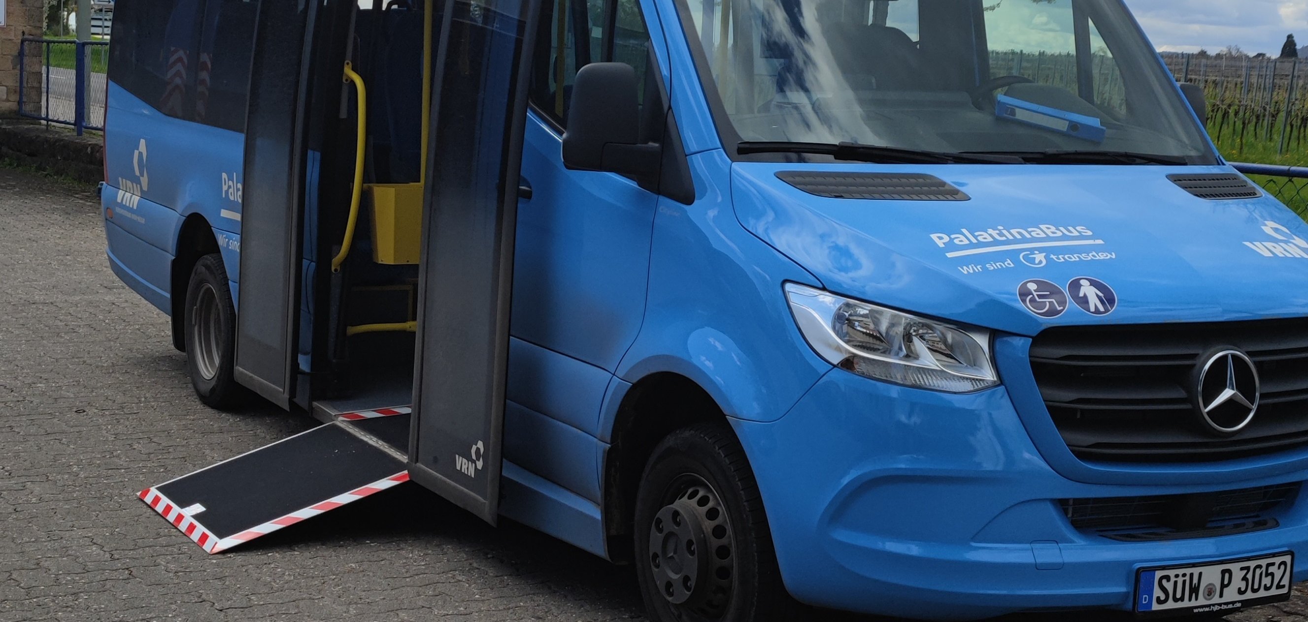 Ein Kleinbus der Palatina Bus GmbH steht mit geöffneter Tür und ausgefahrener Einstiegsrampe auf einem Parkplatz.
