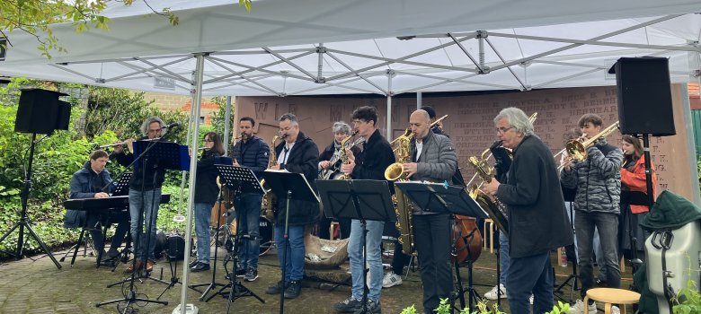 Das deutsch-französische Jazzensemble spielte zum dritten Mal ein Europakonzert anlässlich des 5. Mai. Foto: KV SÜW Ein deutsch-französisches Jazzensemble spielt unter einem weißen Pavillon. Die Musiker, die verschiedene Blasinstrumente und ein Klavier spielen, stehen und sitzen in einer Reihe. Die Aufführung findet in einem grünen Garten statt.