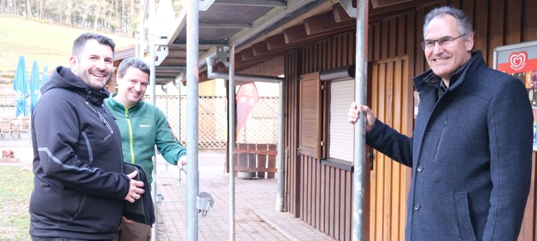 Landrat Dietmar Seefeldt (rechts) machte sich im Februar gemeinsam mit Steven Barth vom Gebäudemanagement der Kreisverwaltung und Wildpark-Geschäftsführer Daniel Kraus vor Ort ein Bild vom Gebäude und den Arbeiten. Foto: KV SÜW Landrat Dietmar Seefeldt, Steven Barth vom Gebäudemanagement der Kreisverwaltung und Wildpark-Geschäftsführer Daniel Kraus besichtigen die Arbeiten am Verwaltungsgebäude des Wild- und Wanderparks Südliche Weinstraße in Silz. Vor dem Gebäude ist ein Gerüst aufgebaut.