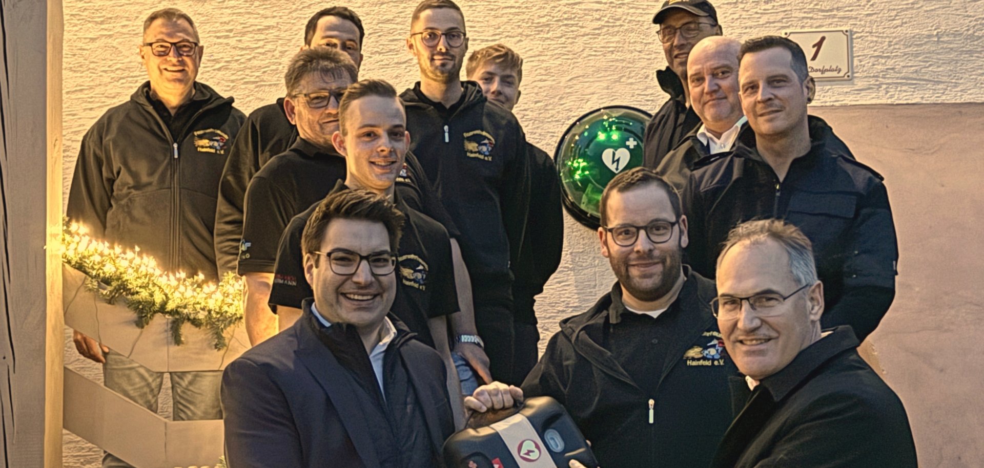 Landrat Dietmar Seefeldt und Sparkassenvorstandsmitglied Benjamin Hirsch  überreichen Ralf Bamesberger, frisch wiedergewählter Wehrführer der Freiwilligen Feuerwehr Hainfeld, das AED-Gerät.