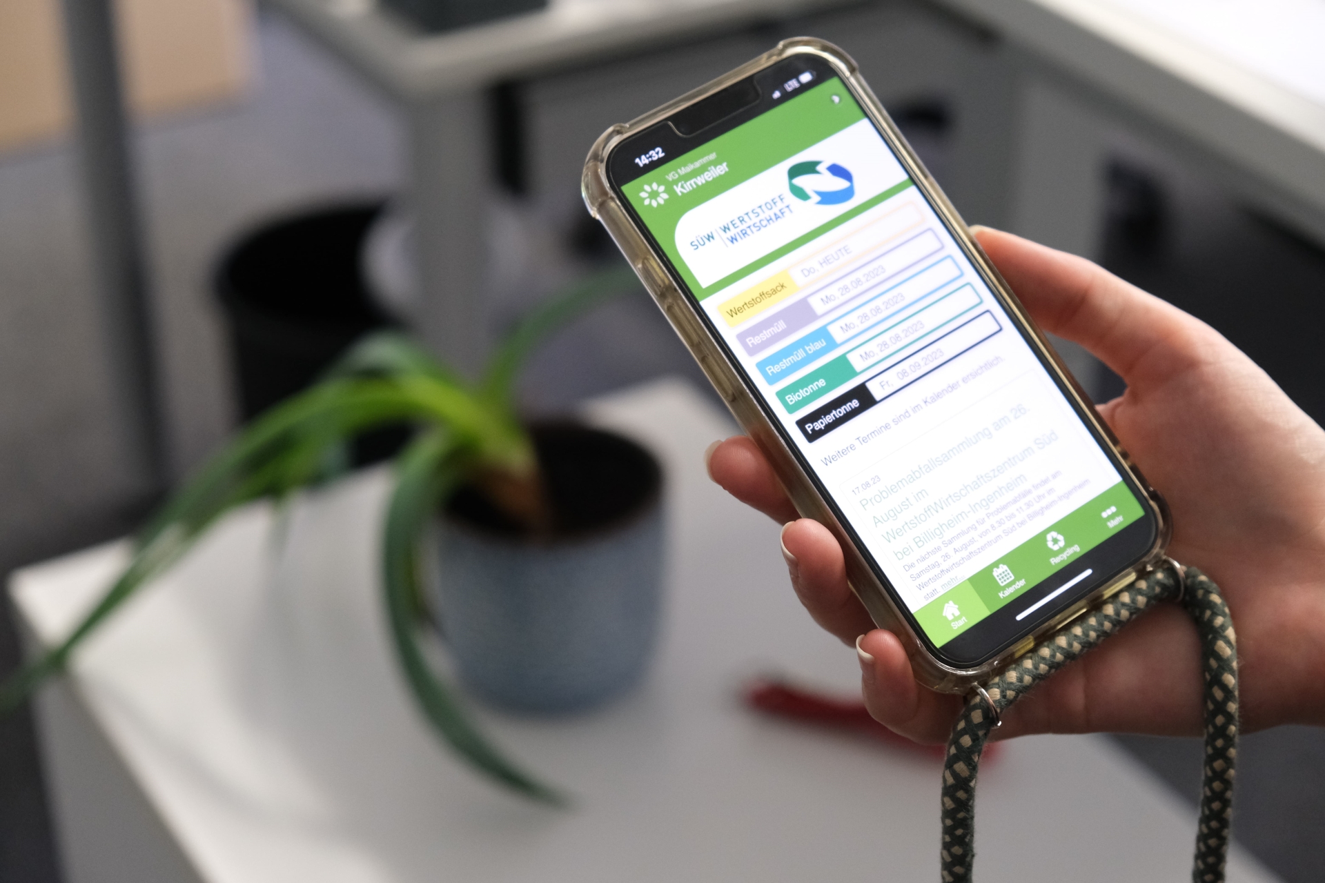 Eine Hand hält ein Smartphone, darauf die geöffnete Wertstoff-App.