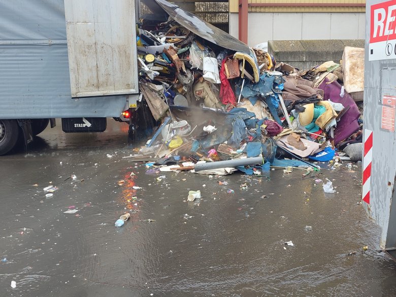 Müll fällt aus einer Heckklappe eines Lkw.