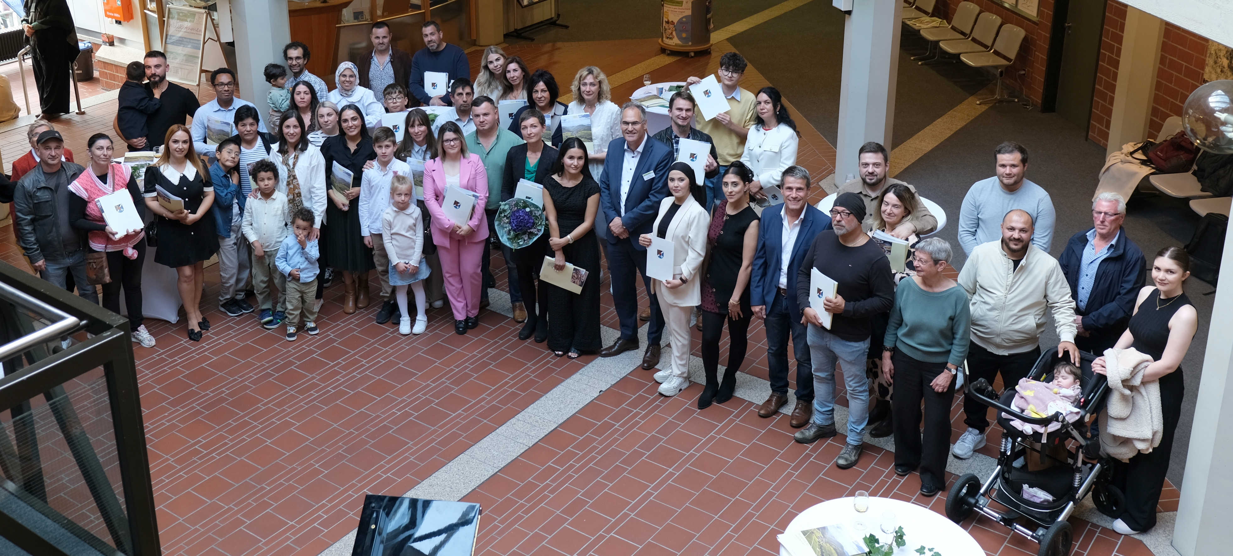 Eine Gruppe frisch eingebürgerter deutscher Staatsbürgerinnen und Staatsbürger steht im Foyer des Kreishauses in Landau. 