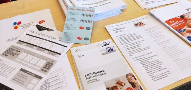 Infomaterialien liegen auf einem Tisch verteilt.