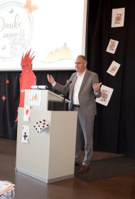 Landrat Dietmar Seefeldt auf einer Bühne vor einem Rednerpult und bedankt sich bei der langjährigen Schulleiterin Ingrid Baumgartner-Schmitt für ihren Einsatz.